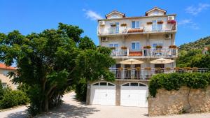 a tall building with umbrellas in front of it at Apartments Tonći and Iris in Primošten