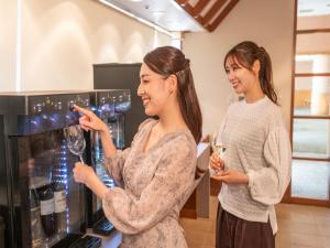two women looking at wine glasses in a wine machine at KAMENOI HOTEL Genkainada All-Inclusive Resort in Kitakyushu +119 photos