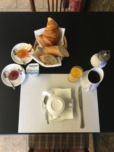 a table with a plate of bread and a cup of coffee at Hôtel Au Val De Saône PARKING GRATUIT in Sathonay-Camp