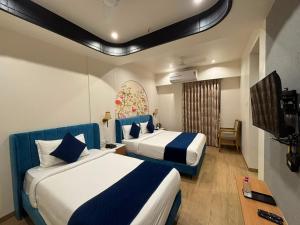 a hotel room with two beds and a flat screen tv at Hotel Royal Galleria in Vadodara