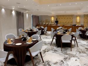 a restaurant with tables and chairs and a man in the background at Hotel Royal Galleria in Vadodara