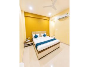 a bedroom with a bed and a yellow wall at HOTEL MEDHYA GRAND Near Goḏawalia Chauraha - 200 Meter From Baba Vishwanath Temple & Ganga Arti Ghat ! Wi-Fi #Lift #Hygiene & Spacious Room - BEST HOTEL IN VARANASI in Varanasi +8 photos