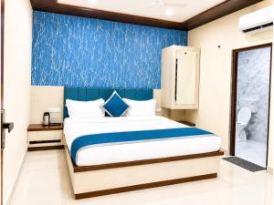 a bedroom with a bed and a blue wall at HOTEL MEDHYA GRAND Near Goḏawalia Chauraha - 200 Meter From Baba Vishwanath Temple & Ganga Arti Ghat ! Wi-Fi #Lift #Hygiene & Spacious Room - BEST HOTEL IN VARANASI in Varanasi