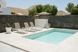 a swimming pool with lounge chairs and a fence at Villa La Genuina in Yaiza