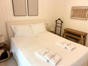 a bedroom with a white bed with two towels on it at CasaSmaragdi in Perdika
