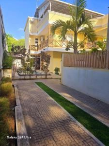a house with a palm tree in front of a brick road at Logement des palmiers in Flic-en-Flac