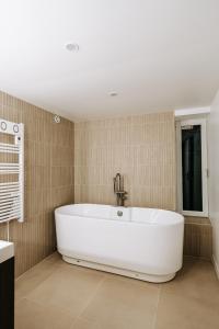 a large white bath tub in a bathroom at La Parenthèse Maisonneuve in Troyes