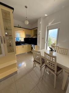 a kitchen with a table and two chairs and a window at Ksamil Guest House Dea in Ksamil
