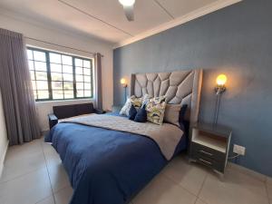a bedroom with a large bed with blue sheets and pillows at The Wave House on the Beach in Port Alfred