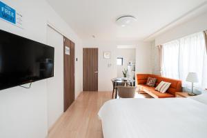 a hotel room with a bed and a television on a wall at Maple Hotel Tokyo in Tokyo