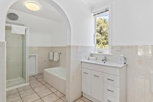 a white bathroom with a tub and a sink and a shower at Riverfront Motel & Restaurant in Hobart
