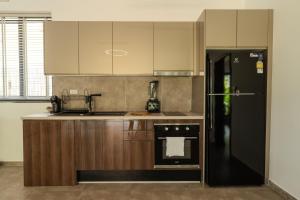 a kitchen with a black refrigerator and wooden cabinets at Villa Coco Escape in Ko Phangan