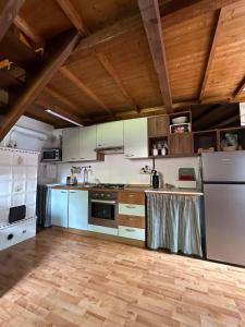 a kitchen with white appliances and wooden ceilings at Baita al sole in Faida
