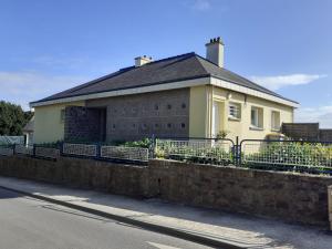 a yellow house with a fence in front of it at L'agapanthe in Plouézec