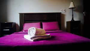 Una cama rosa con sombrero y toallas. en Rez Home Catas Altas en Catas Altas
