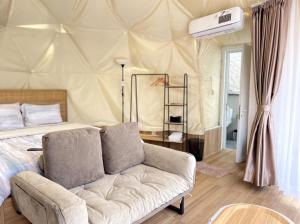 a bedroom with a bed and a couch in a room at Zatura Dome Glamping in Panjadakan