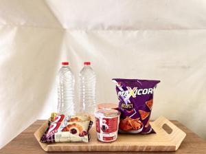 two bottles of water and snacks on a wooden tray at Zatura Dome Glamping in Panjadakan