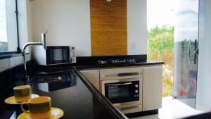 a kitchen with a stove and a microwave and two coffee cups at Rez Home Catas Altas in Catas Altas