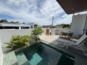 a swimming pool with a chair and a table on a balcony at Big leaf villa cozy in Bangrak Beach
