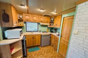 a kitchen with wooden cabinets and a sink and a dishwasher at La cabane Proche circuit in Le Castellet