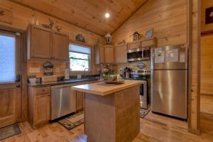 a kitchen with wooden cabinets and a stainless steel refrigerator at Squirrels Hideaway Fire Pit MTN Views in Copperhill