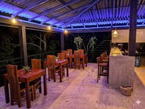 a restaurant with wooden tables and chairs and purple lighting at FlyOn Resort in Dickwella