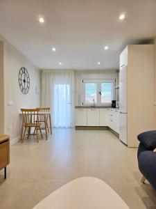 a kitchen and living room with white cabinets and chairs at LURDE Apartamentos Rurales in El Cerezal