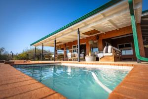 a swimming pool in front of a house at Rockfig Lodge Madikwe in Madikwe Game Reserve