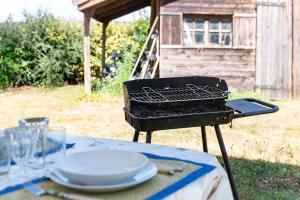 a barbecue grill with a table with plates on it at Chez Daniel Et Zdenka in Villars-les-Dombes