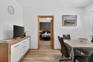 a living room with a table and a television on a dresser at Suite Stadtgrün in Papenburg