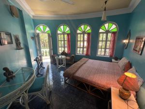 a bedroom with a bed and a table and some windows at Villa Rivercat in Mandrem +34 photos