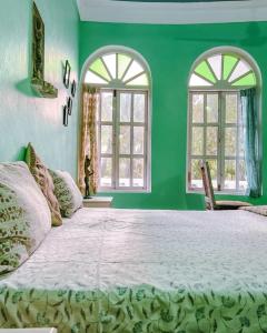 a green bedroom with a large bed with two windows at Villa Rivercat in Mandrem