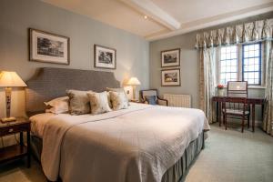 1 dormitorio con 1 cama grande y escritorio en Buckland Manor - A Relais & Chateaux Hotel en Broadway