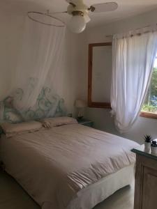 a bedroom with a bed with a ceiling fan and a window at Villa Ira Gongilo R9048 in Porto Rotondo