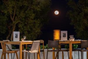 two tables and chairs with a moon in the background at Kamari Beach Hotel in Kamari