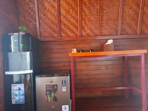 a refrigerator next to a wooden wall next to a table at Suwehan Rey Cliff House in Nusa Penida