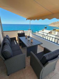 a patio with a table and chairs and the ocean at Thea in Myrtos
