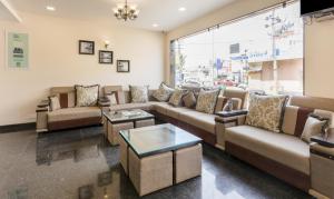 a living room with couches and tables and a large window at Hotel Sunrise Luxury Stays in Chikmagalūr
