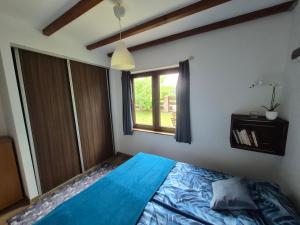 a bedroom with a blue bed and a window at Chatki u Patki in Łebieniec