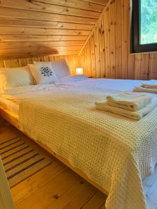 a bed in a wooden room with towels on it at Chalet Mignon - Aproka adorable small guest house in Sicasău