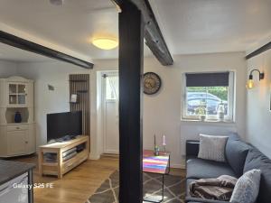 a living room with a couch and a tv at Ferielejlighed Solbakke in Østermarie