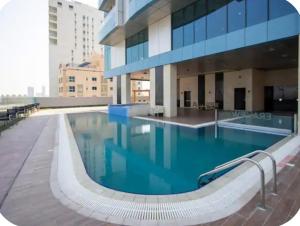 a large swimming pool in front of a building at Sea View Apartment in Era View in Manama