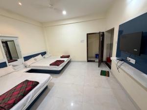 a room with two beds and a flat screen tv at Shada Shiv Heritage, Omkareshwar in Godarpura