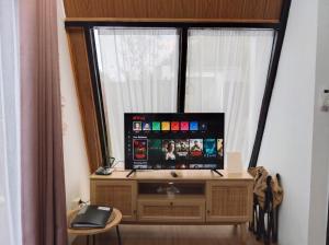 a television sitting on a stand in front of a window at Villa Kahuripan Triangle in Bandung