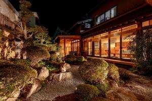 a garden with bushes and a building at night at Villa Taniguchi in Takayama
