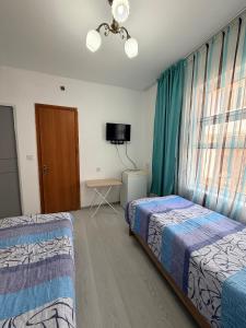 a hotel room with two beds and a television at Jibek Murok in Bosteri