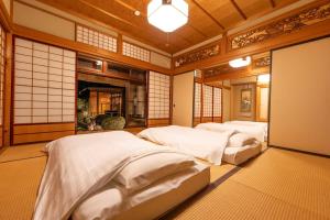 two beds in a room with white sheets at Villa Taniguchi in Takayama