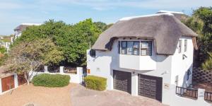 a white house with a thatched roof at La Casita House in St Francis Bay
