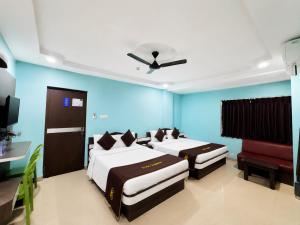 two beds in a room with blue walls at Hotel The Four Square in Digha