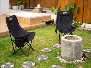 two black chairs sitting in the grass in a yard at Maple Dome Glamping in Bandung